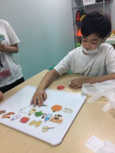 買ってくるものリストに書いてあるものをホワイトボードに並べる男の子②